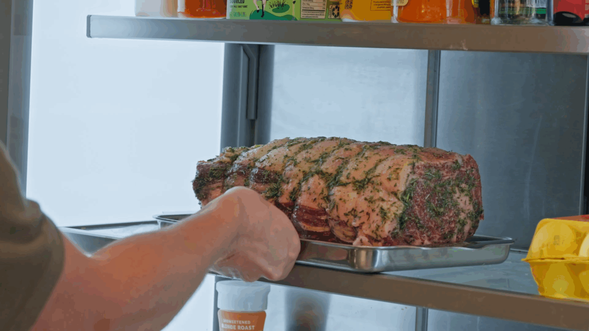 Nick DiGiovanni transferring a seasoned prime rib to the fridge.