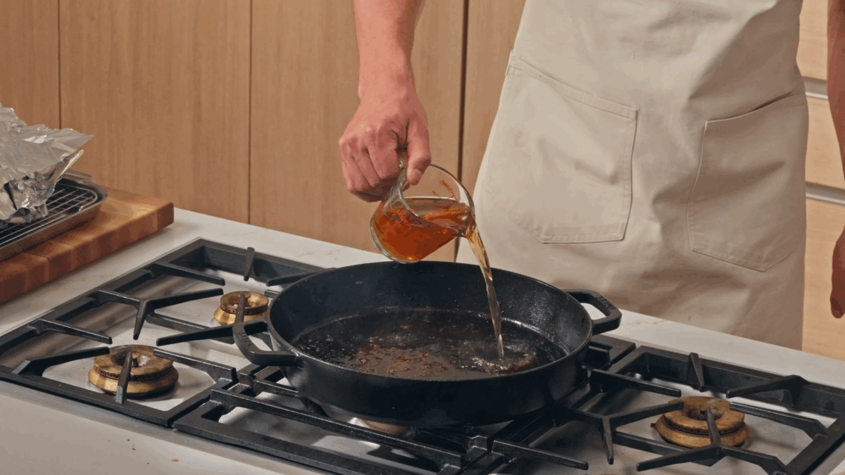 Nick DiGiovanni pouring stock into a cast-iron skillet.