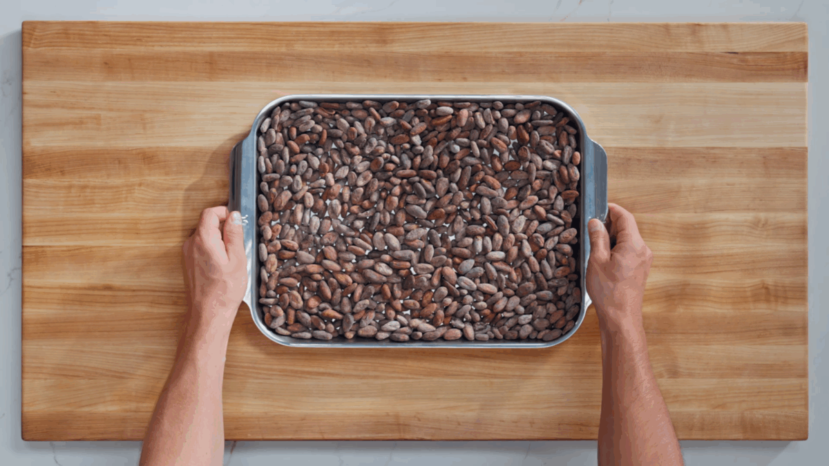 Nick DiGiovanni holding a sheet tray of dry cacao beans. 