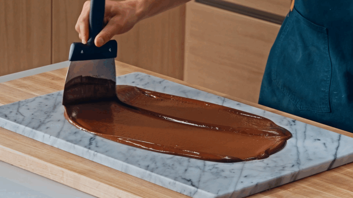 Nick DiGiovanni spreading homemade chocolate on a marble slab. 