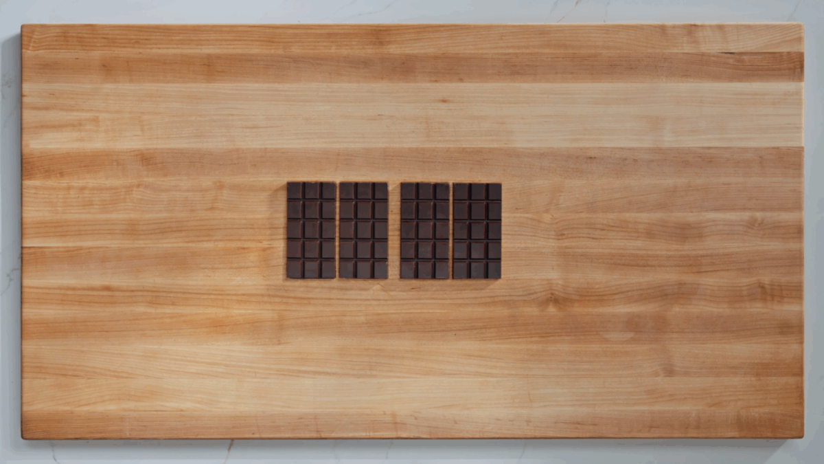 Four homemade chocolate bars on a wooden table. 