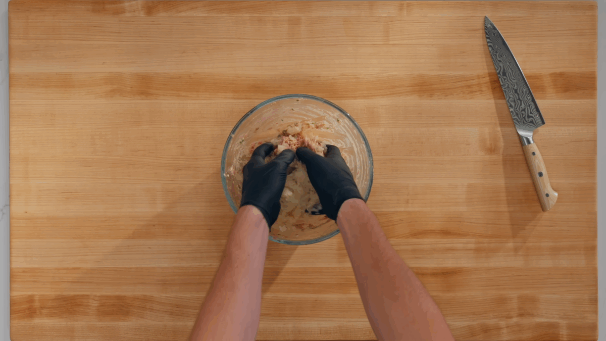 Nick DiGiovanni mixing the pork filling in a bowl with two hands. 