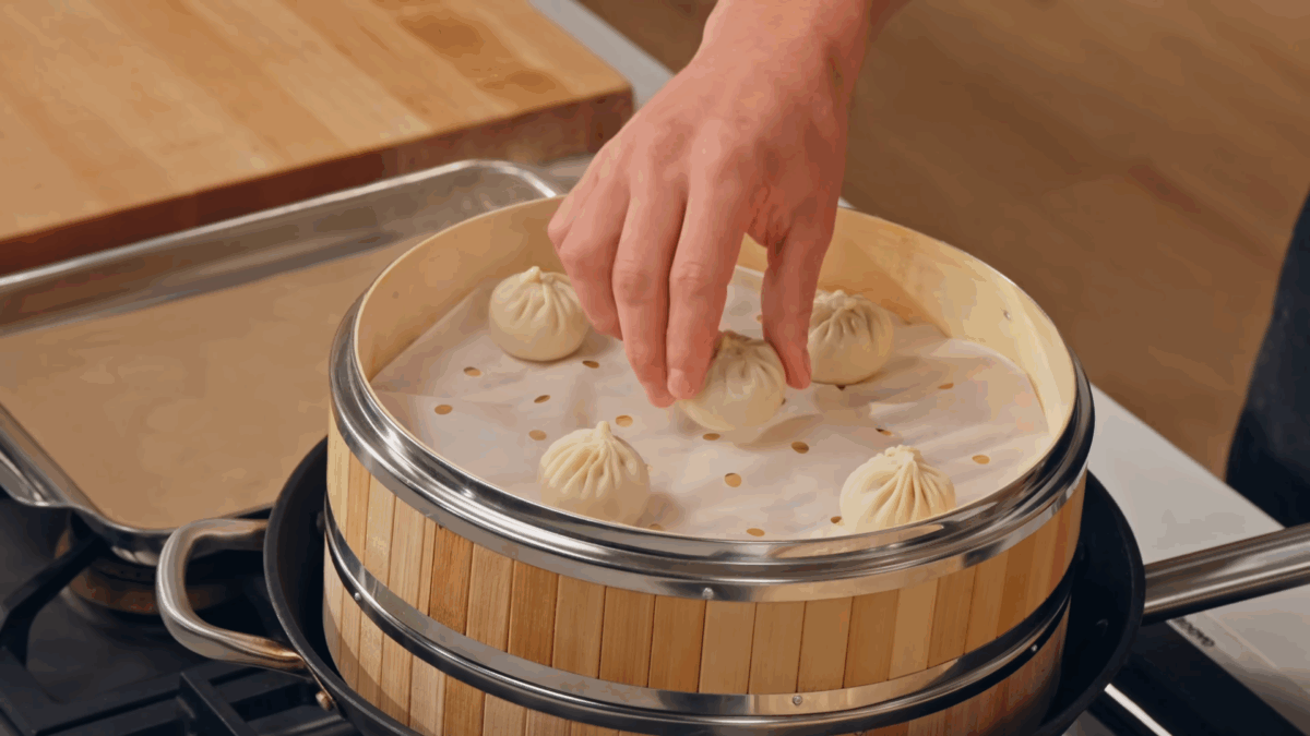 Nick DiGiovanni placing pork soup dumplings in a steamer basket.