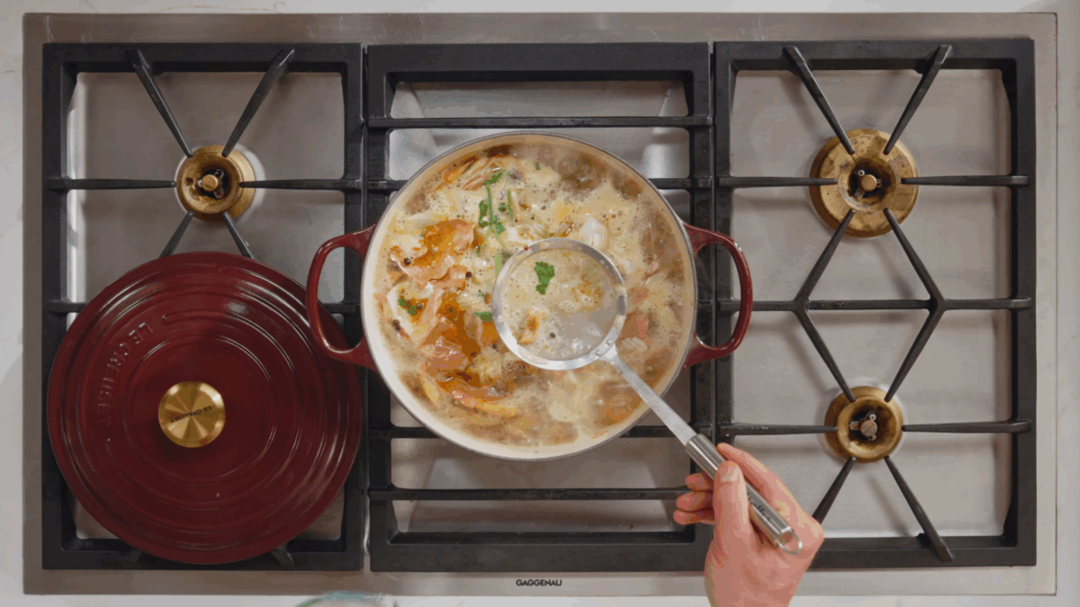 Nick DiGiovanni skimming seafood broth.