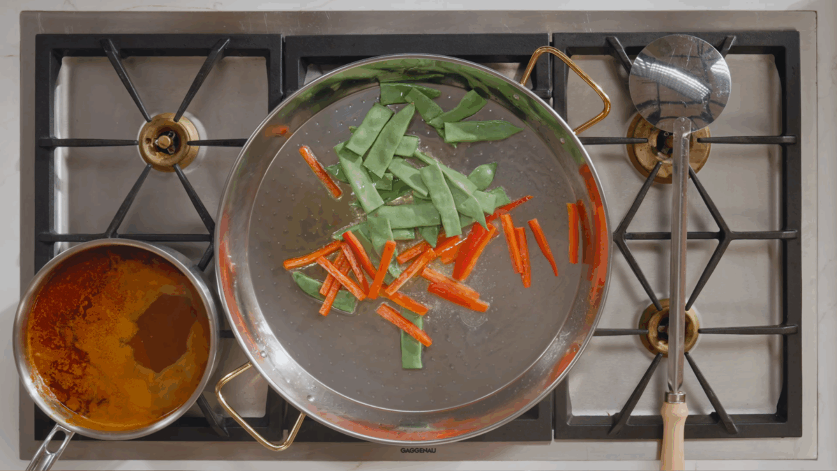 Green beans and bel peppers blistering in a pan on the stovetop. 