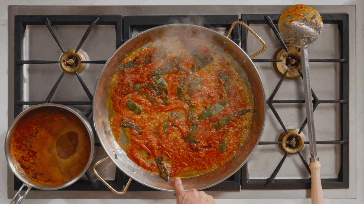 Paella simmering in a pan on the stovetop. 