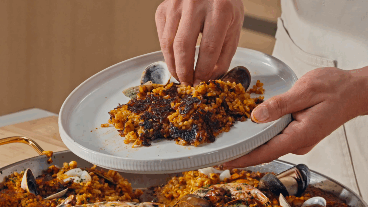 Nick DiGiovanni plating Spanish seafood paella, showing the crispy bottom. 