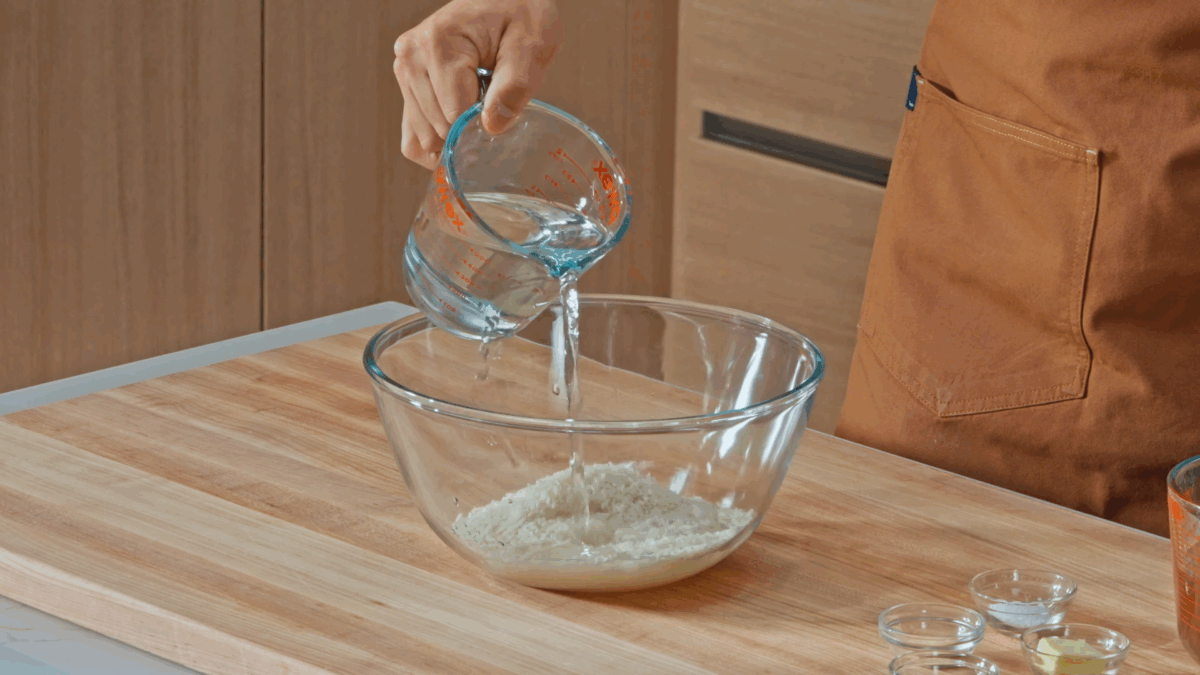Nick DiGiovanni pouring water over a bowl of uncooked white rice.