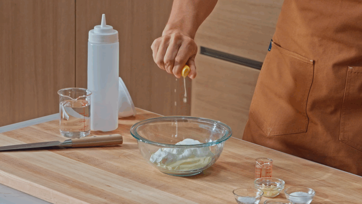 Nick DiGiovanni squeezing lemon juice into a bowl to make halal-style white sauce.
