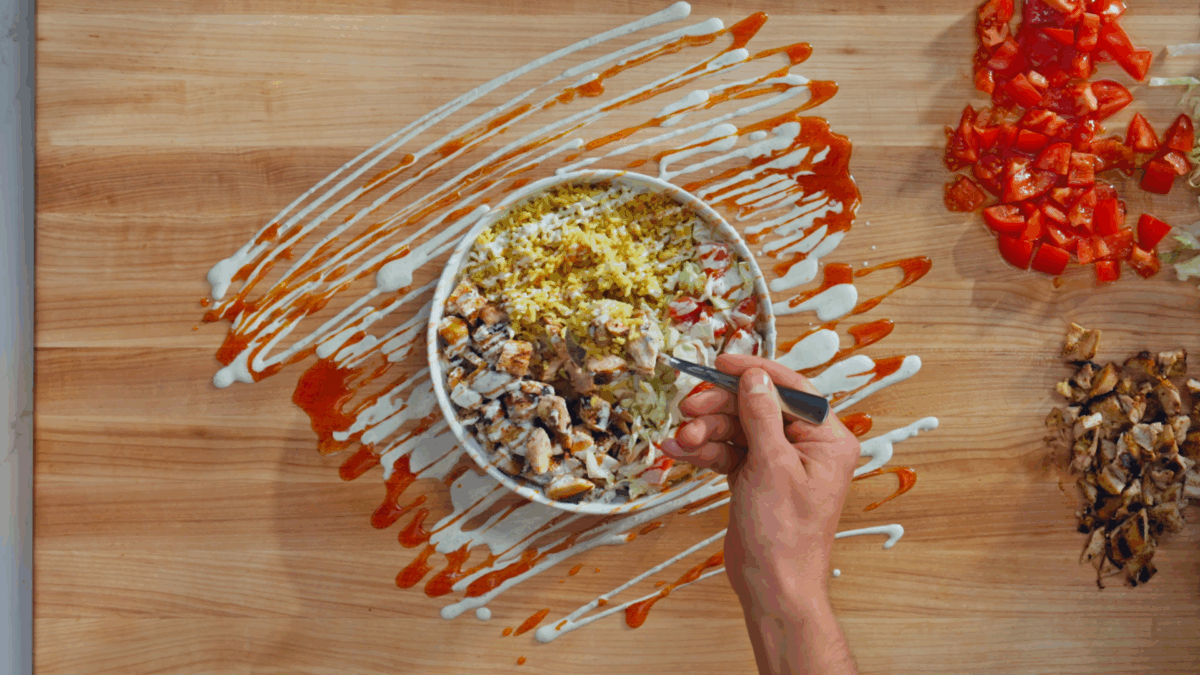 Nick DiGiovanni lifting a bite of halal chicken and rice from a bowl.