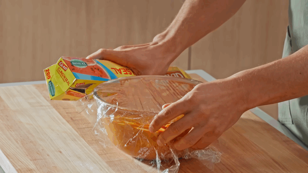Nick DiGiovanni covering a bowl of tandoori marinade coated chicken with plastic wrap. 