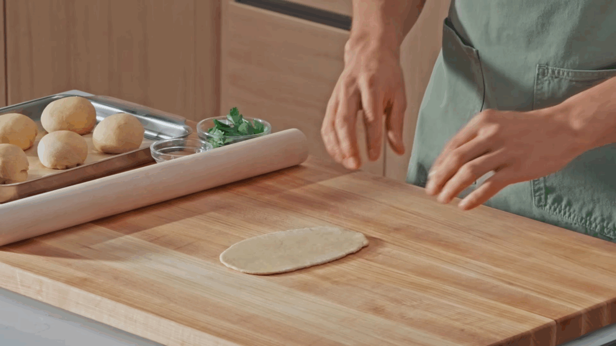 Nick DiGiovanni rubbing water over naan dough. 