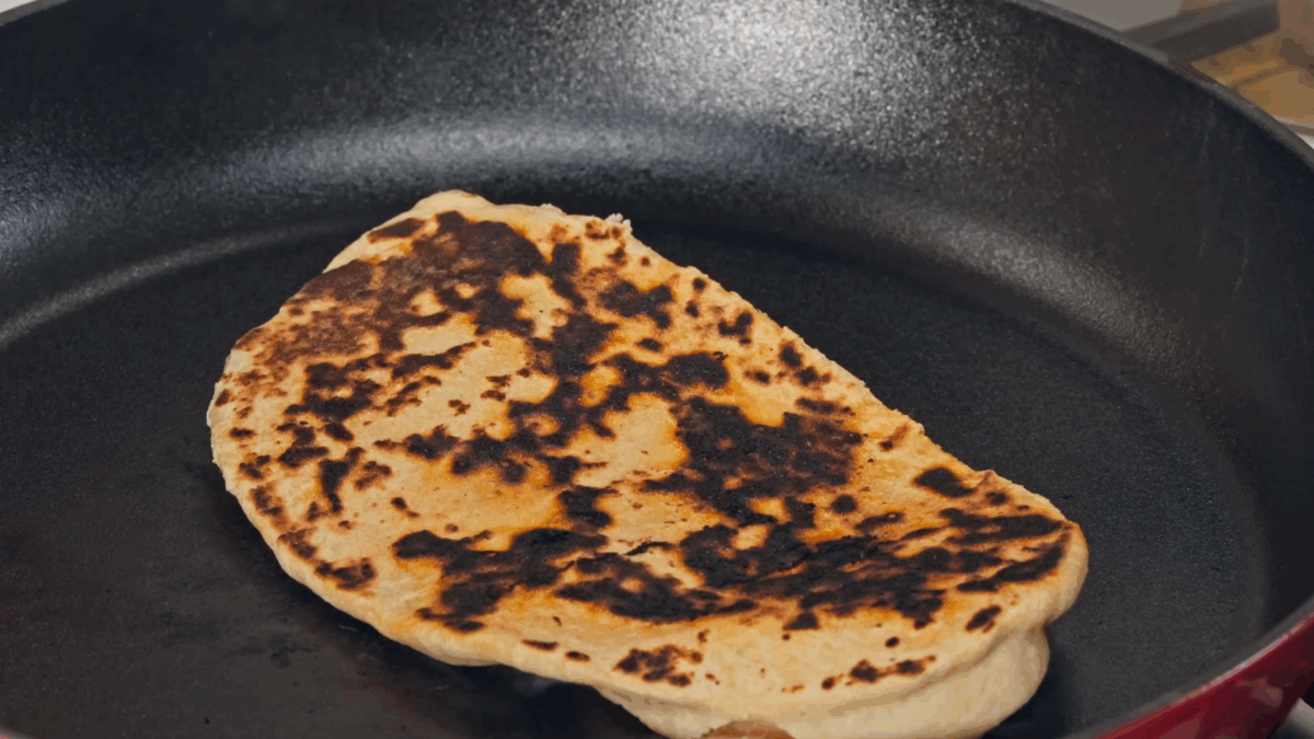Naan cooking in a cast-iron skillet. 
