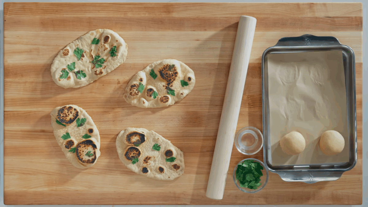 Four pieces of naan on a wooden table. 