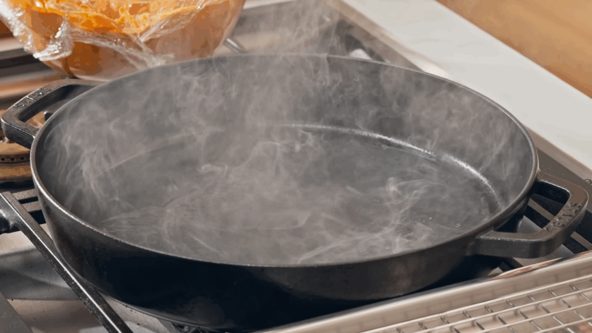 A cast-iron pan smoking on a stovetop. 