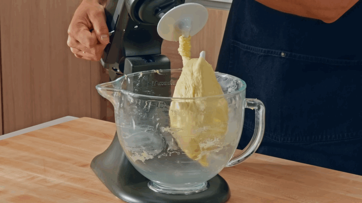 Hamburger bun dough in a stand mixer fit with a dough hook.