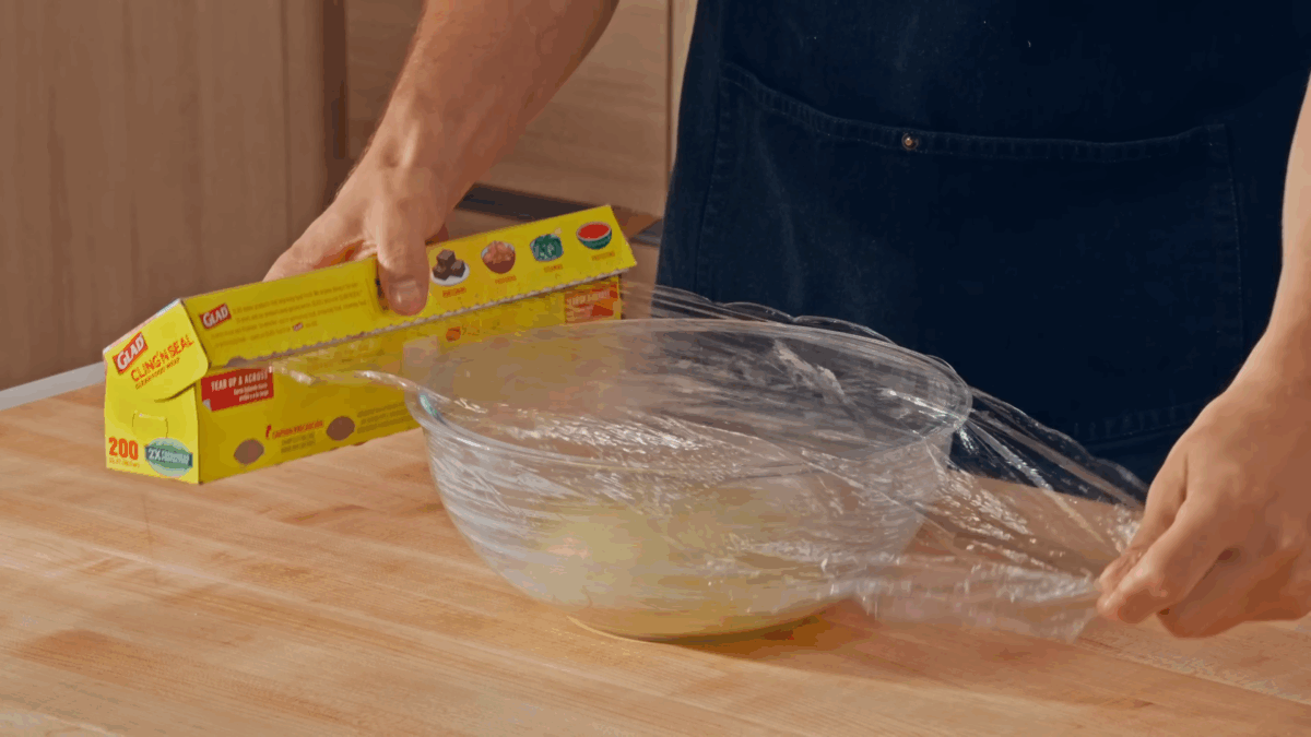 Nick DiGiovanni covering a bowl of hamburger dough with plastic wrap.