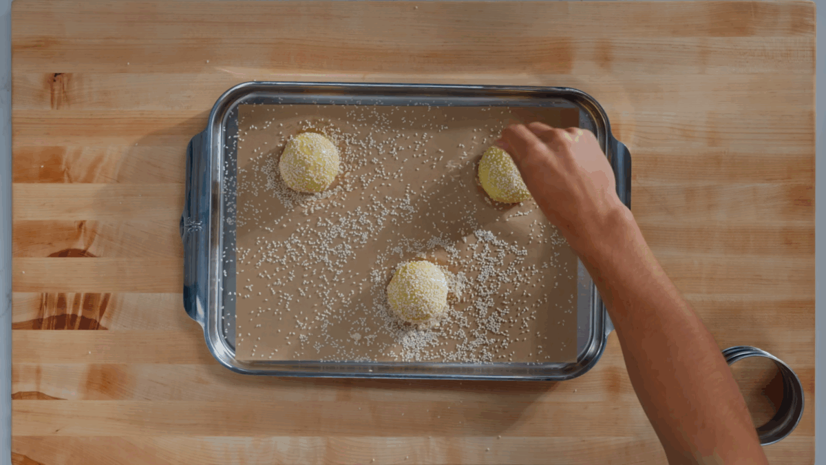 Nick DiGiovanni topping hamburger buns with sesame seeds.