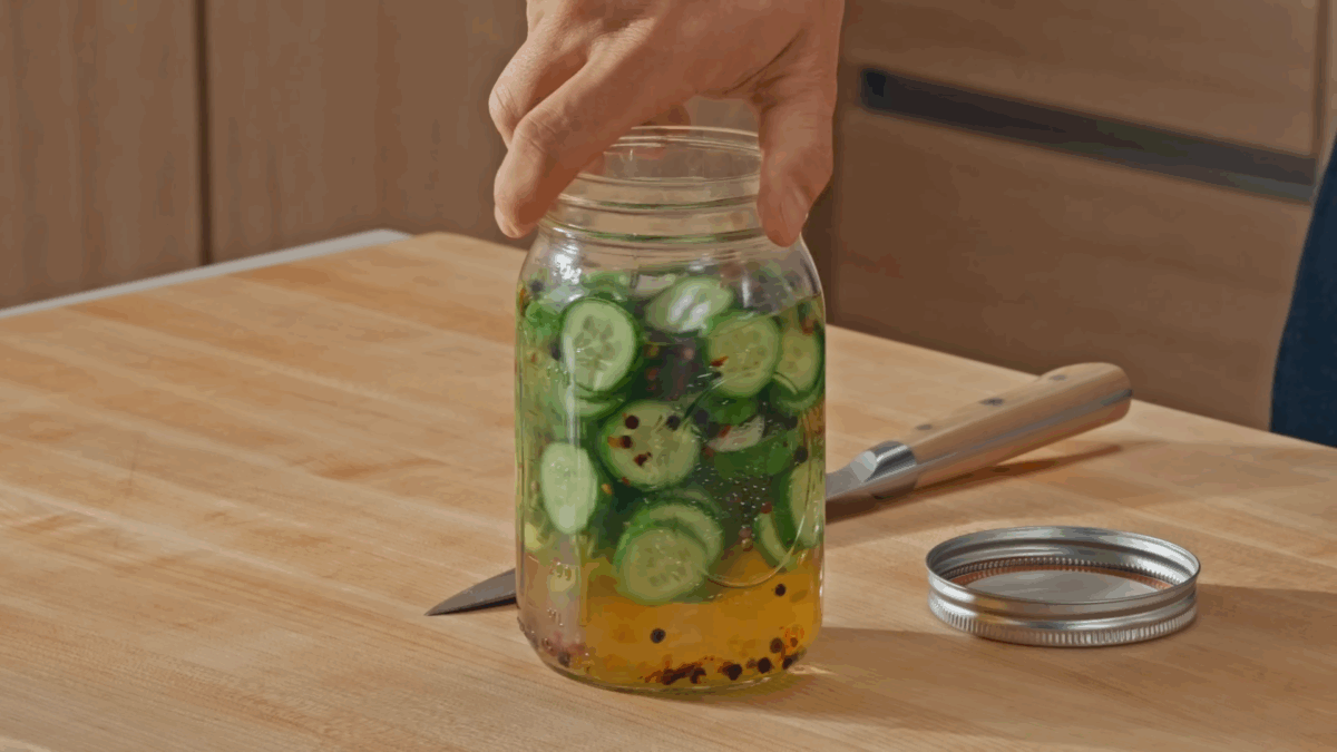 Nick DiGiovanni holding a jar of homemade quick pickles.
