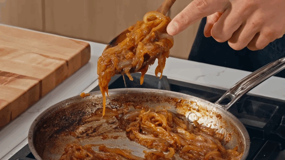 Nick DiGiovanni lifting a scoop of caramelized onions from a skillet.