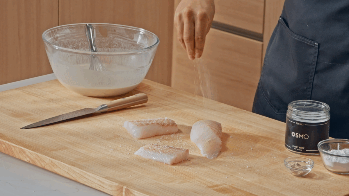 Nick DiGiovanni seasoning cod filets with salt.