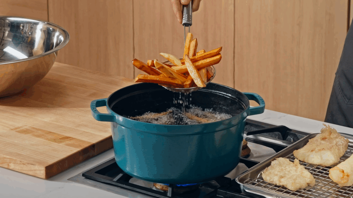 Nick DiGiovanni using a spider to lift chips from a pot of oil.