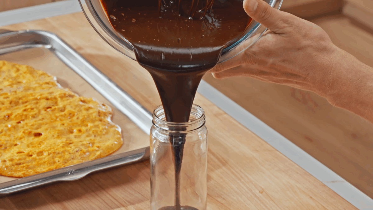 Nick DiGiovanni pouring chocolate sauce in a jar, honeycomb candy in the background.