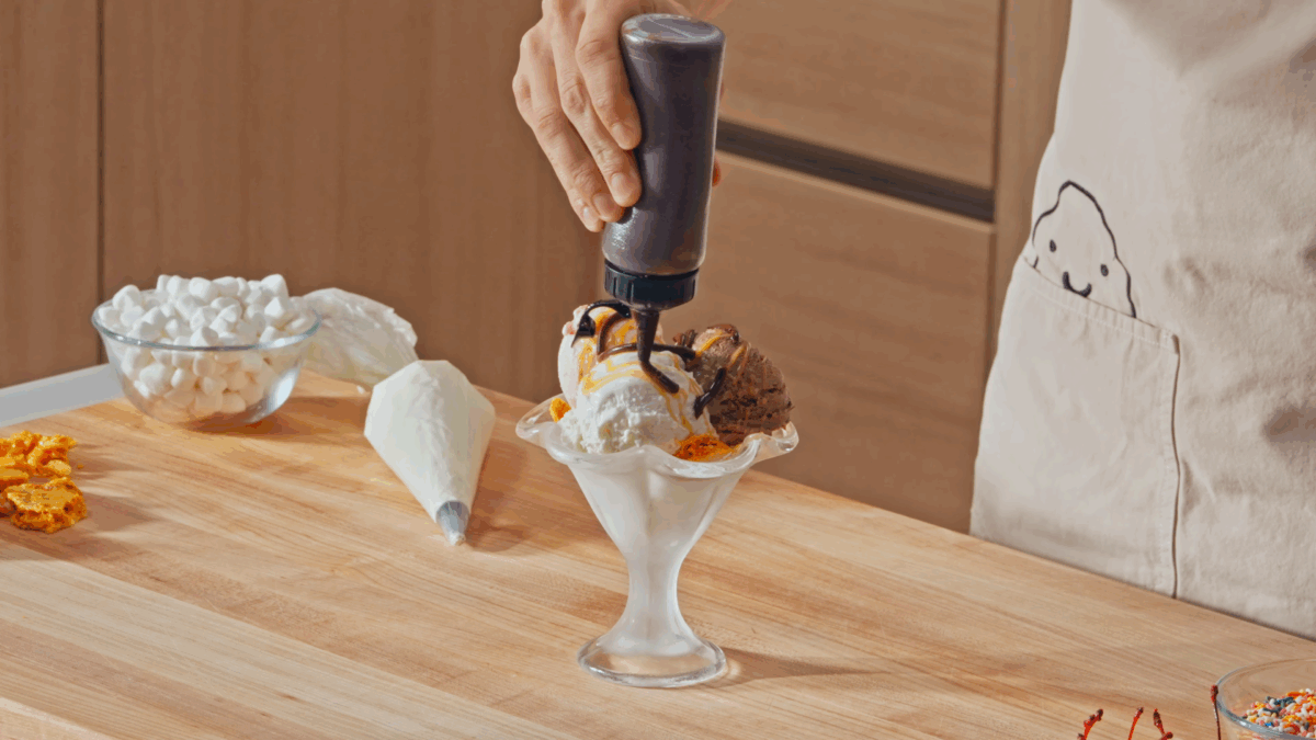 Nick DiGiovanni adding hot fudge sauce to an ice cream sundae.