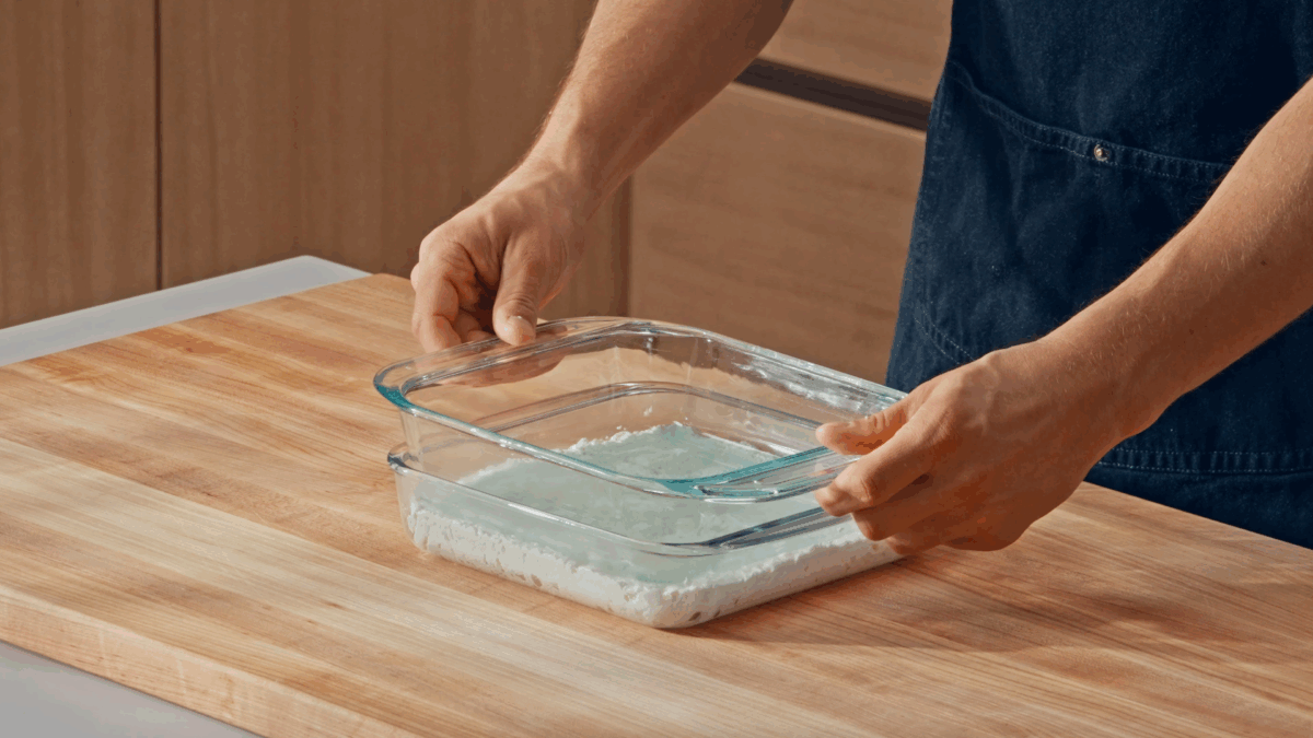 Nick DiGiovanni pressing fresh paneer in a square baking dish. 