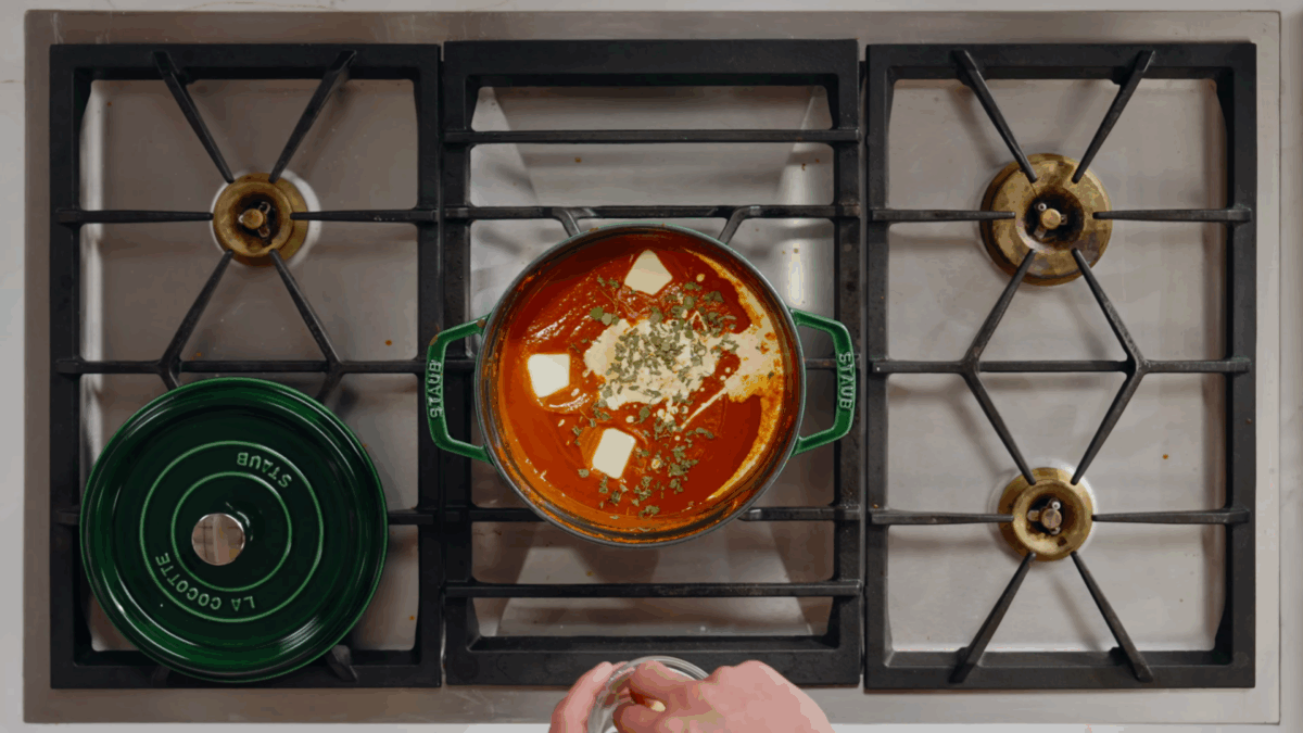 Nick DiGiovanni combining paneer butter masala ingredients in a pot on the stovetop. 