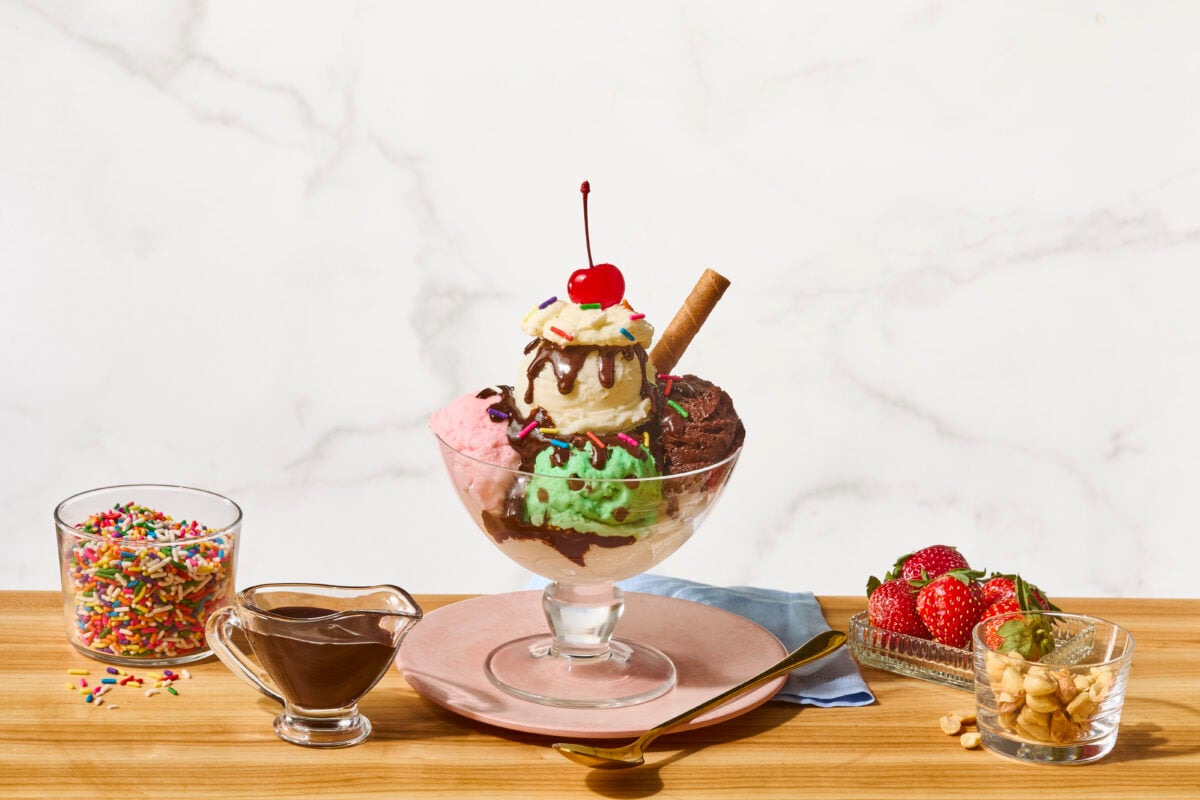 A homemade ice cream sundae with vanilla, chocolate, and strawberry ice cream, hot fudge sauce, caramel, and whipped cream.