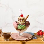 A homemade ice cream sundae with vanilla, chocolate, and strawberry ice cream, hot fudge sauce, caramel, and whipped cream.