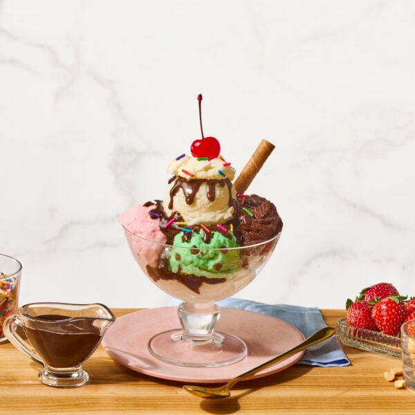 A homemade ice cream sundae with vanilla, chocolate, and strawberry ice cream, hot fudge sauce, caramel, and whipped cream.