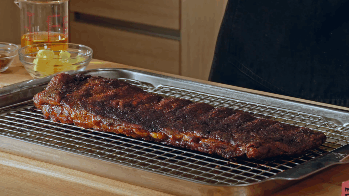 A rack of St. Louis style pork ribs on a wire rack on top of a baking sheet.