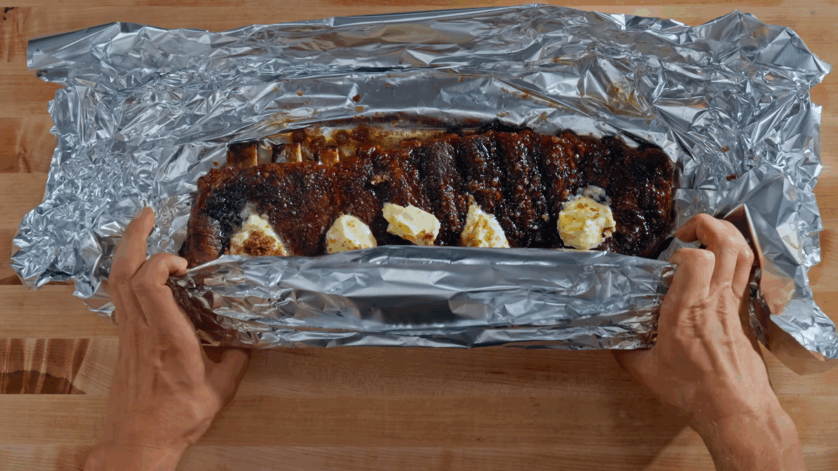 Nick DiGiovanni wrapping pork ribs with aluminum foil.