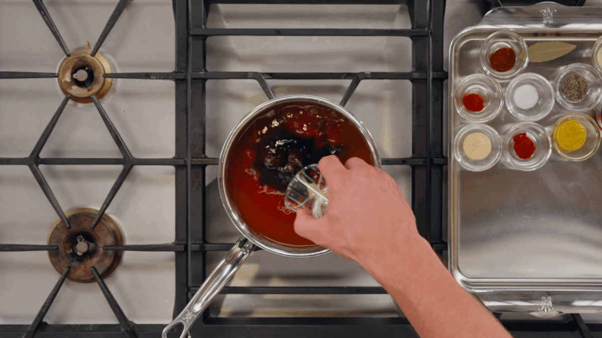 Nick DiGiovanni combining BBQ sauce ingredients in a pan on the stovetop.