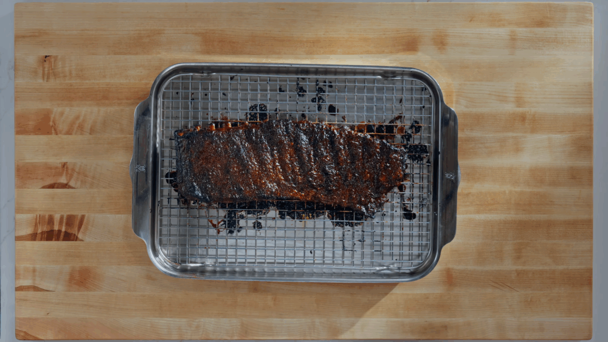 A rack of St. Louis style pork ribs on a wire rack lined sheet tray.