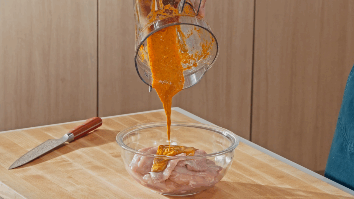 Nick DiGiovanni pouring marinade over raw chicken thighs in a bowl. 
