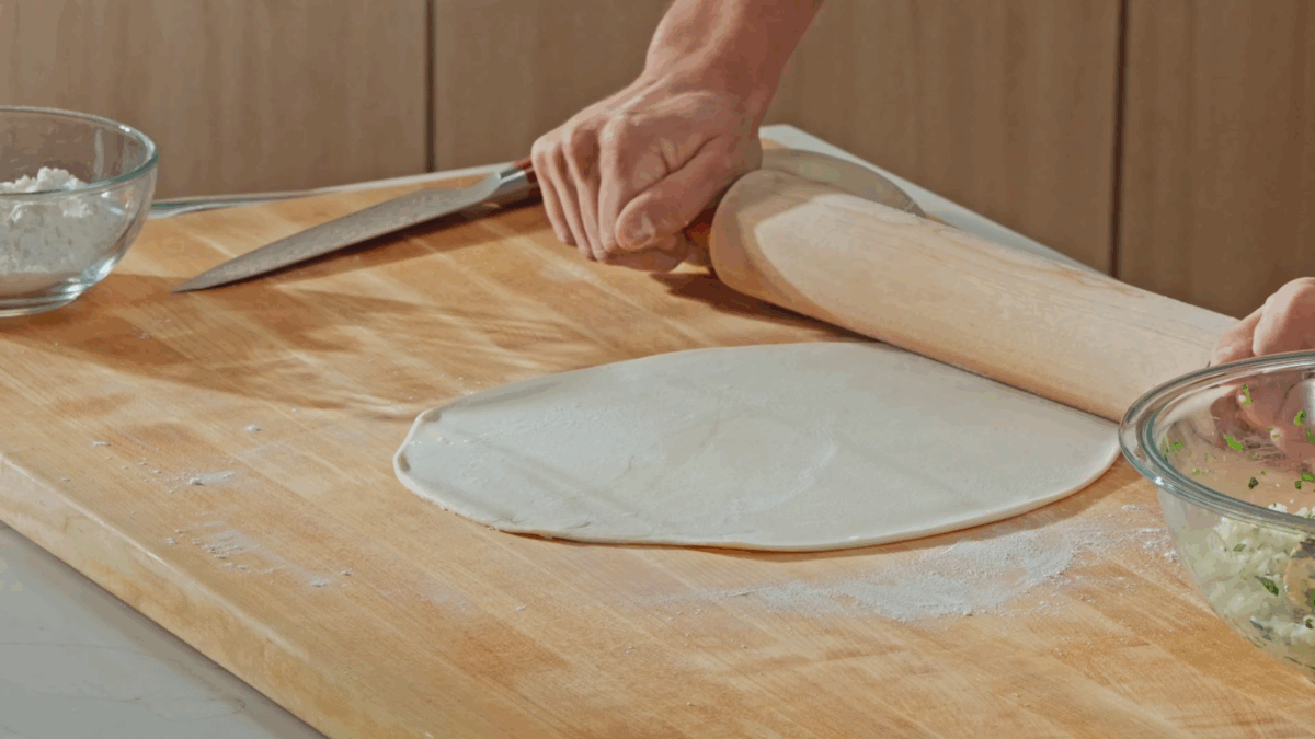 Nick DiGiovanni using a rolling pin to roll and shape flour tortilla dough. 