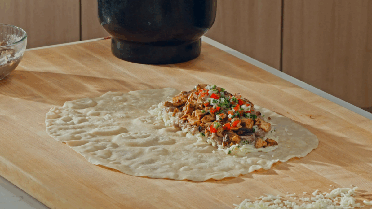 Nick DiGiovanni layering chicken burrito ingredients on a tortilla. 