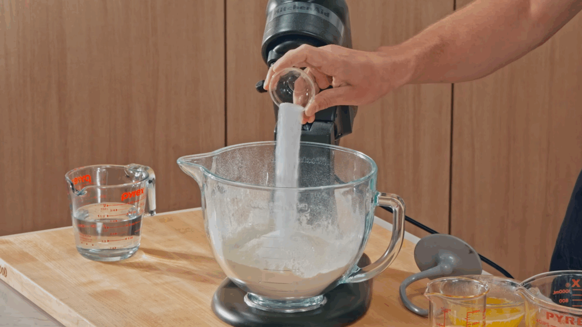 Nick DiGiovanni combining dry ingredients for pizza dough in astand mixer. 