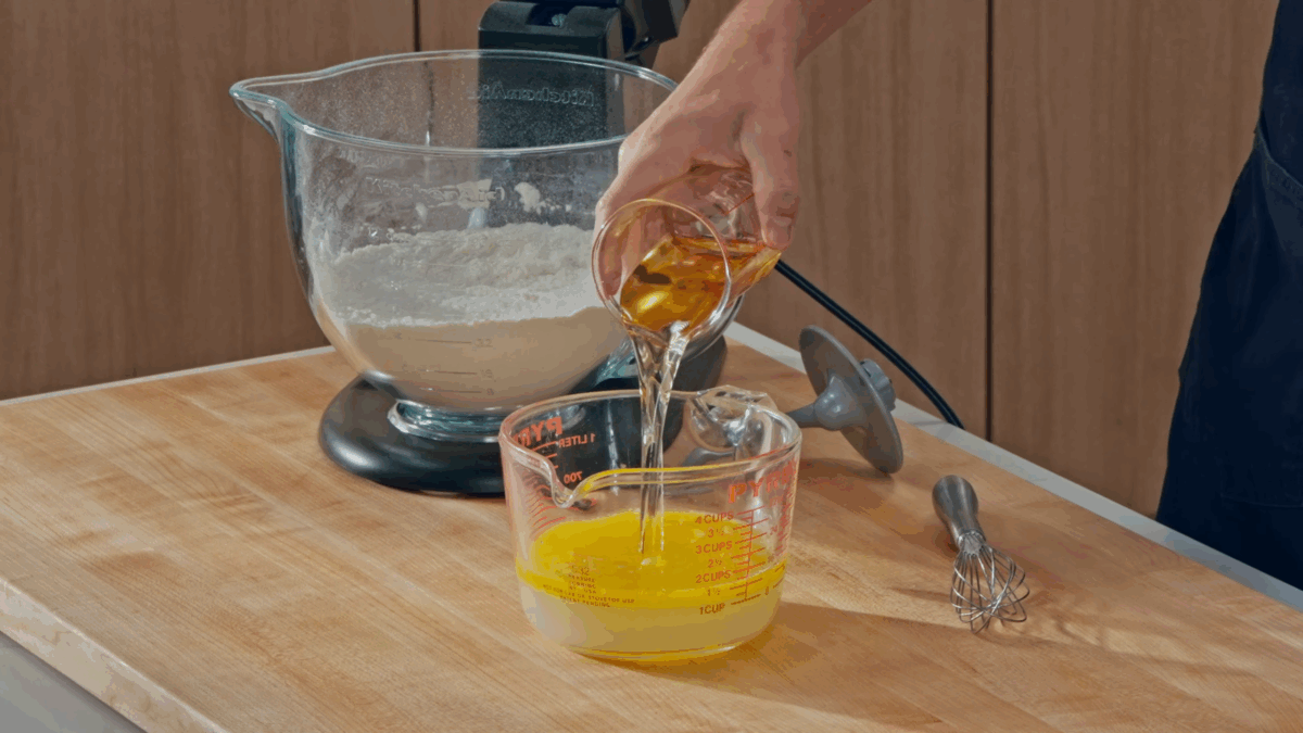 Nick DiGiovanni combining wet ingredients for pizza dough in a glass measuring cup. 