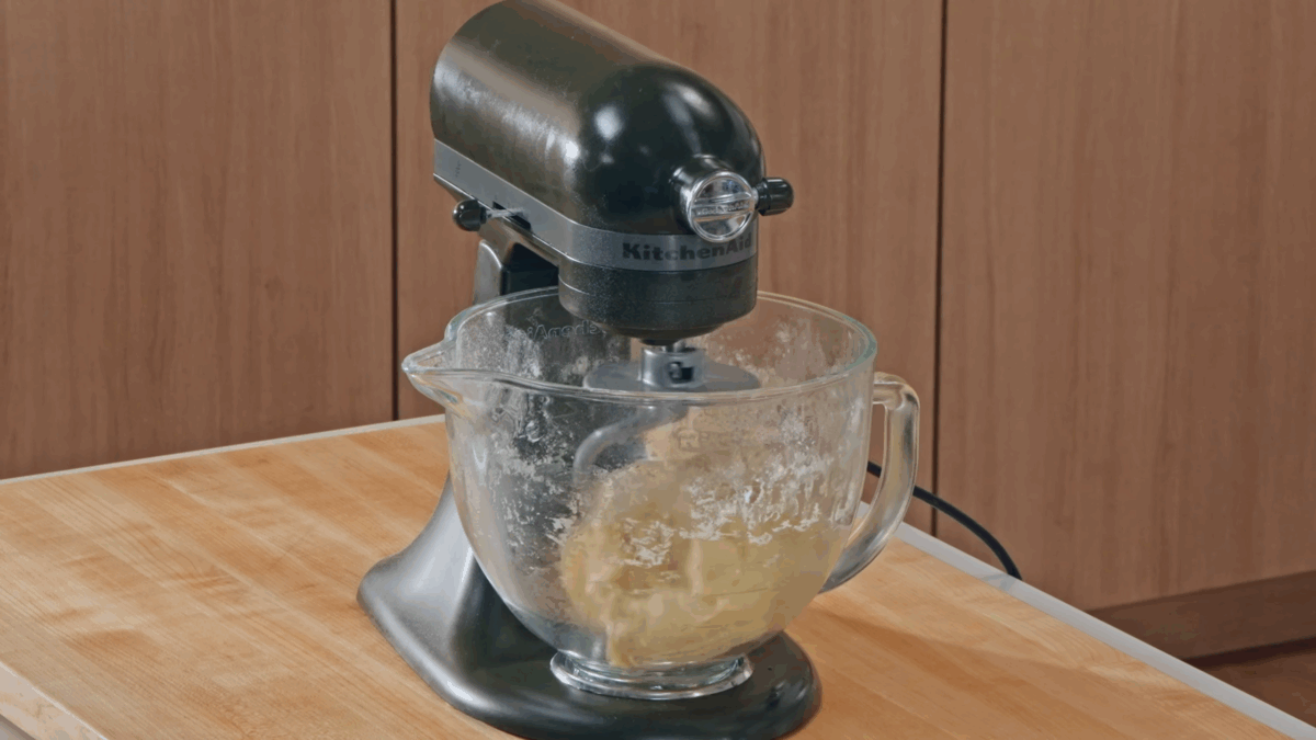 Deep dish pizza dough being kneaded in the bowl of a stand mixer. 