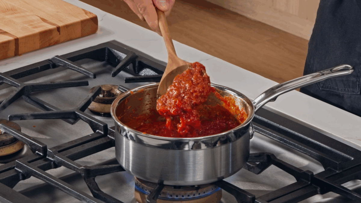 Nick DiGiovanni cooking pizza sauce in a pan on the stovetop.