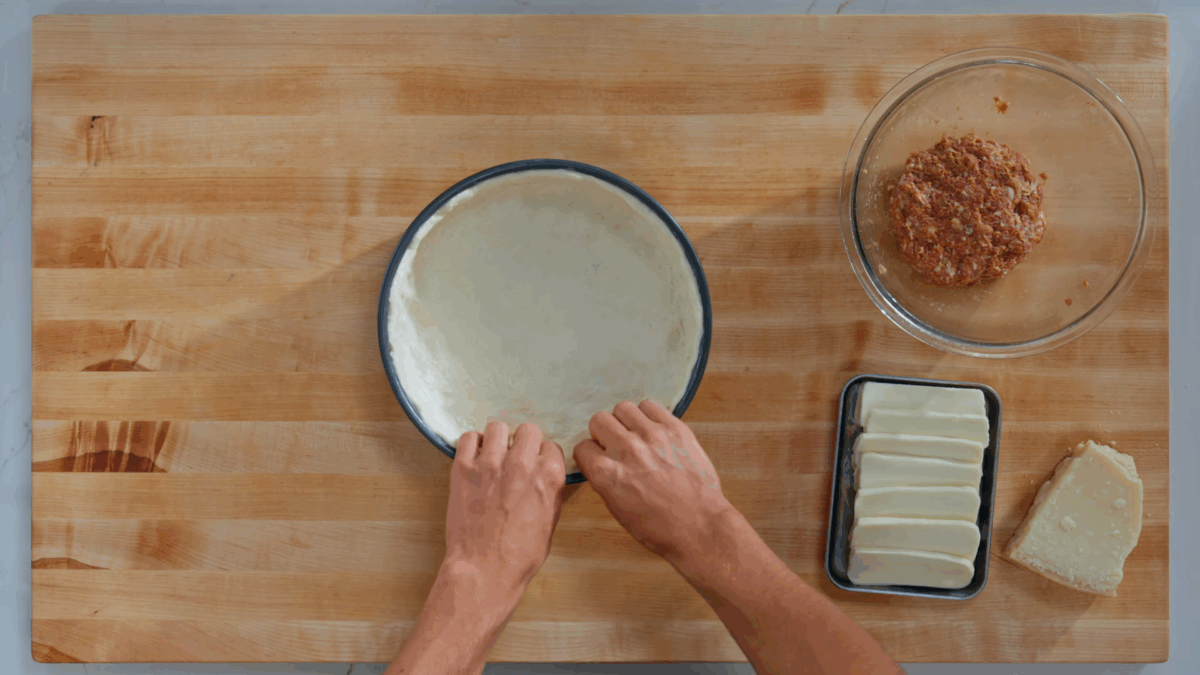 Nick DiGiovanni pressing deep dish pizza dough into a pan. 