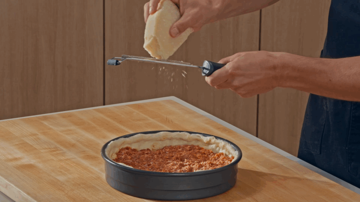 Nick DiGiovanni layering toppings in a deep dish pizza. 