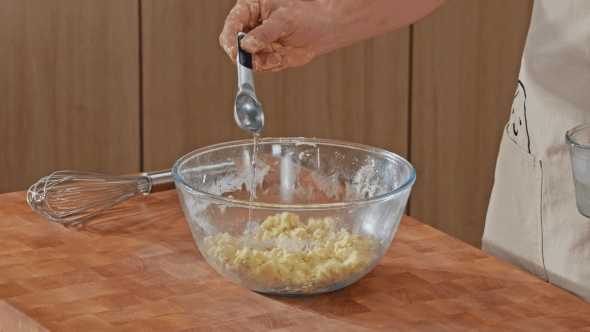Nick DiGiovanni adding cold water to a bowl of pie dough.