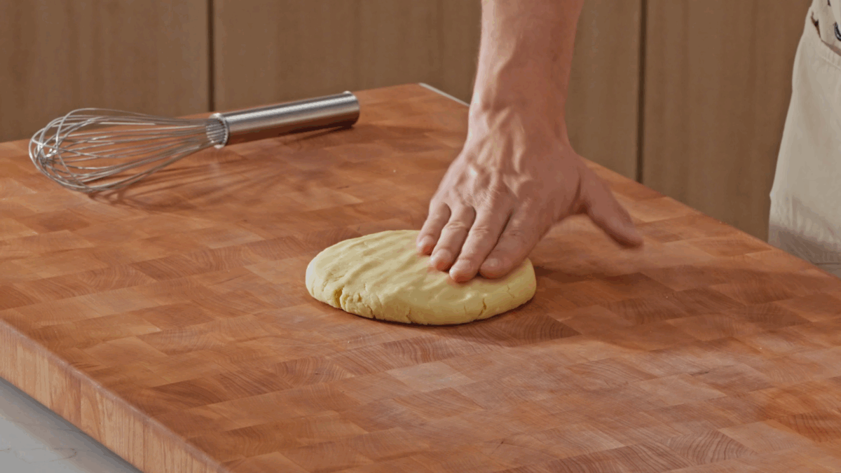 Nick DiGiovanni using a hand to shape pie dough into a disk.