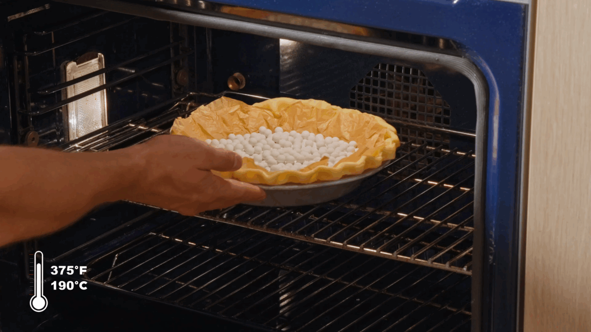 Nick DiGiovanni placing a pie crust filled with pie weights into an oven.