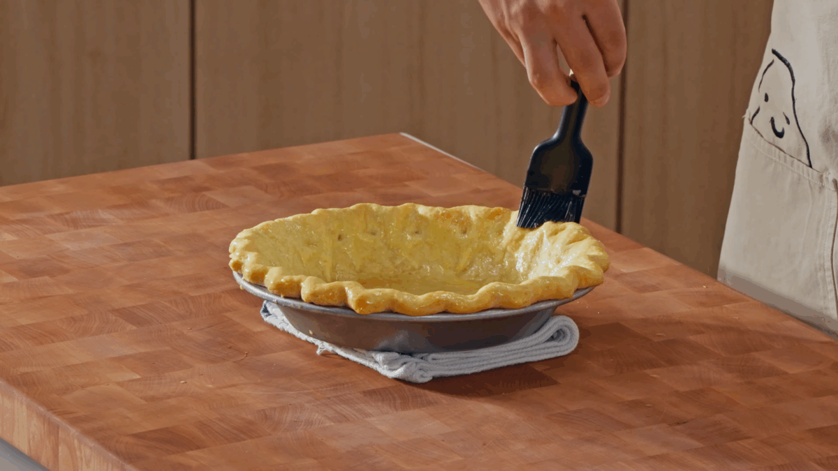 Nick DiGiovanni brushing egg wash over a blind baked pie crust.